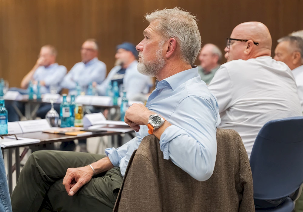 Mann und Frau sitzen bei einer Abendveranstaltung an einem gedeckten Tisch und unterhalten sich, umgeben von Gläsern und Getränken