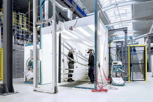 Zwei Mitarbeiter beschichten Aluminium mit Pulver