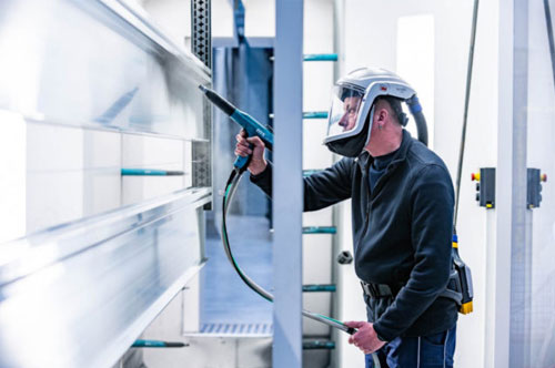 Zwei Mitarbeiter beschichten Aluminium mit Pulver