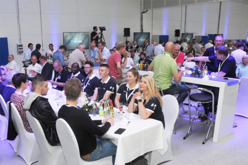 Große Gruppe sitzt an Tischen bei einer Hausmesse