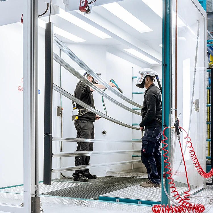 Mitarbeiter von TS Aluminium bei der Pulverbeschichtung von Aluminiumprofilen in der Beschichtungskabine.