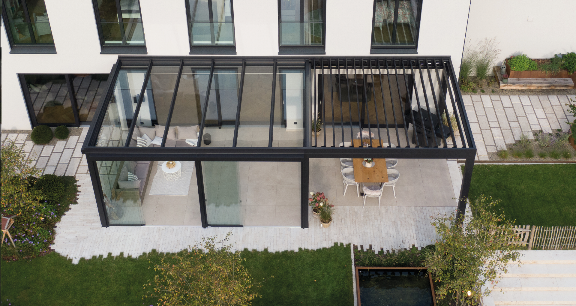 Luftaufnahme einer modernen Terrassenüberdachung mit kombinierter Glasdach- und Lamellendach-Lösung an einem Wohnhaus, flexible Dachvarianten Pult-, Sattel- und Flachdach.