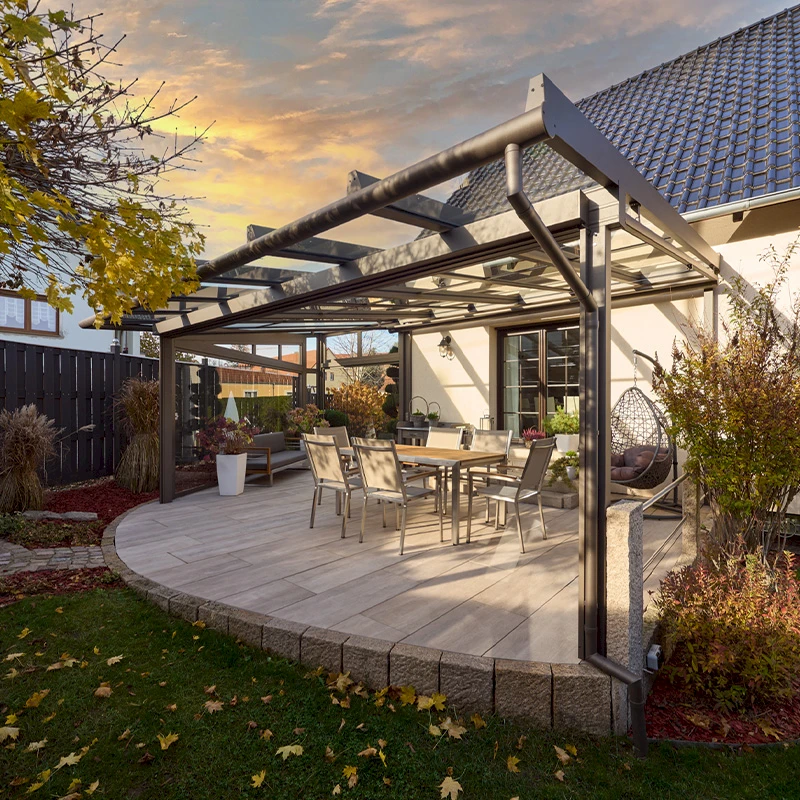 Terrassendach aus Glas und Aluminium mit Esstisch auf runder Holzterrasse
