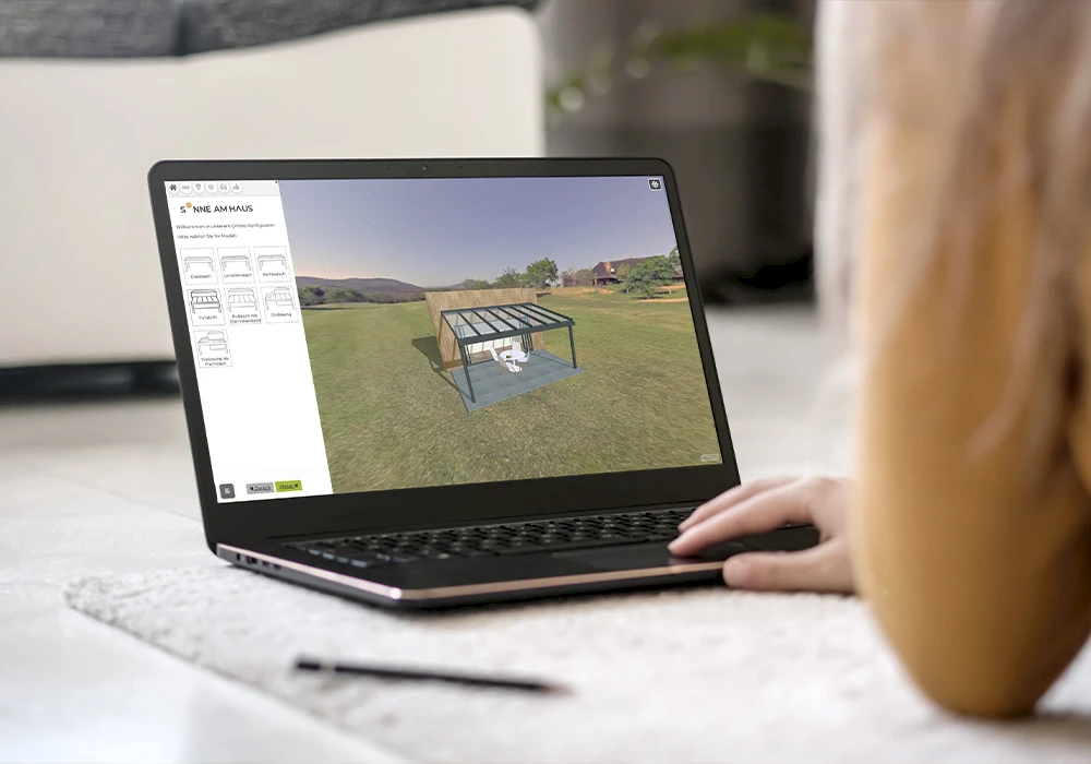 Laptop auf dem Boden mit geöffnetem 3D-Konfigurator für eine Terrassenüberdachung, während eine Person das Modell am Bildschirm anpasst