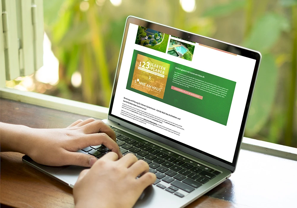 Person tippt auf einem Laptop, auf dem eine Website mit einem grünen Informationsbereich und Gartenbildern angezeigt wird